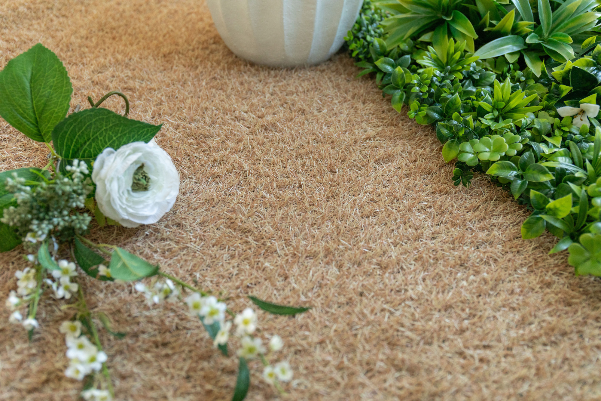 Gazon synthétique de couleur Métropolitain Sable - 22 mm avec fleurs blanches et feuillage vert dans un jardin décoratif
