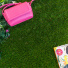 Gazon synthétique Nomade - 34 mm - À raccord scratch, pelouse verte vue de dessus avec sac rose et magazine coloré